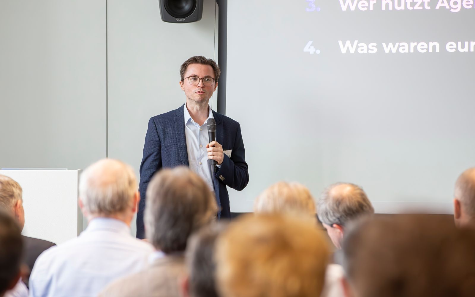 Hendrik Henze speaking into a microphone in front of the audience at the TCI partner meeting